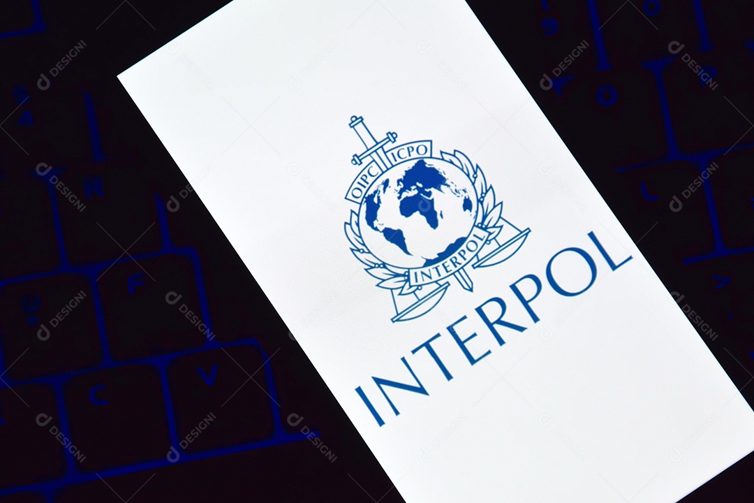 Telefone com logotipo da Interpol exibido na tela sobre fundo de um teclado