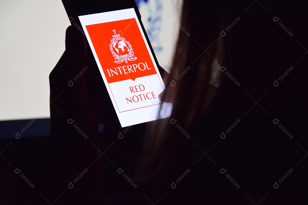 Mulher segurando celular com logotipo da Interpol exibido na tela