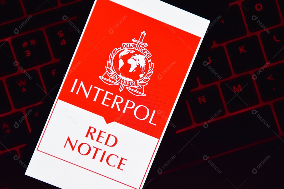 Pessoa segurando telefone com logotipo da Interpol exibido na tela