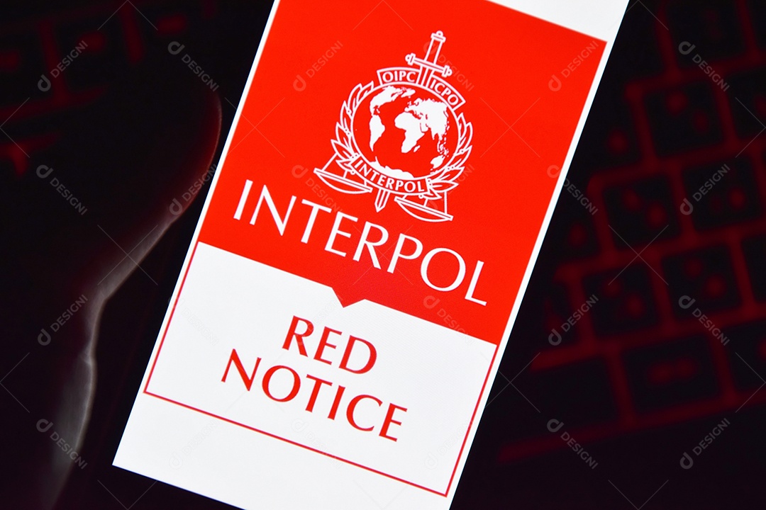 Pessoa segurando smartphone com logotipo da Interpol exibido na tela