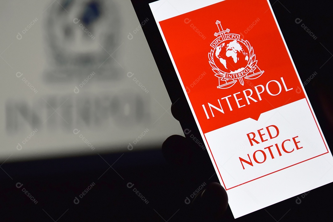 Pessoa segurando celular com logotipo da Interpol exibido na tela