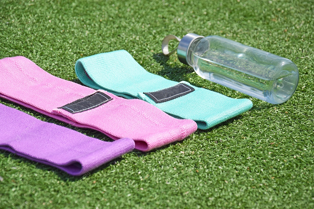 Elásticos de tecido multicolorido e garrafa para fitness na grama