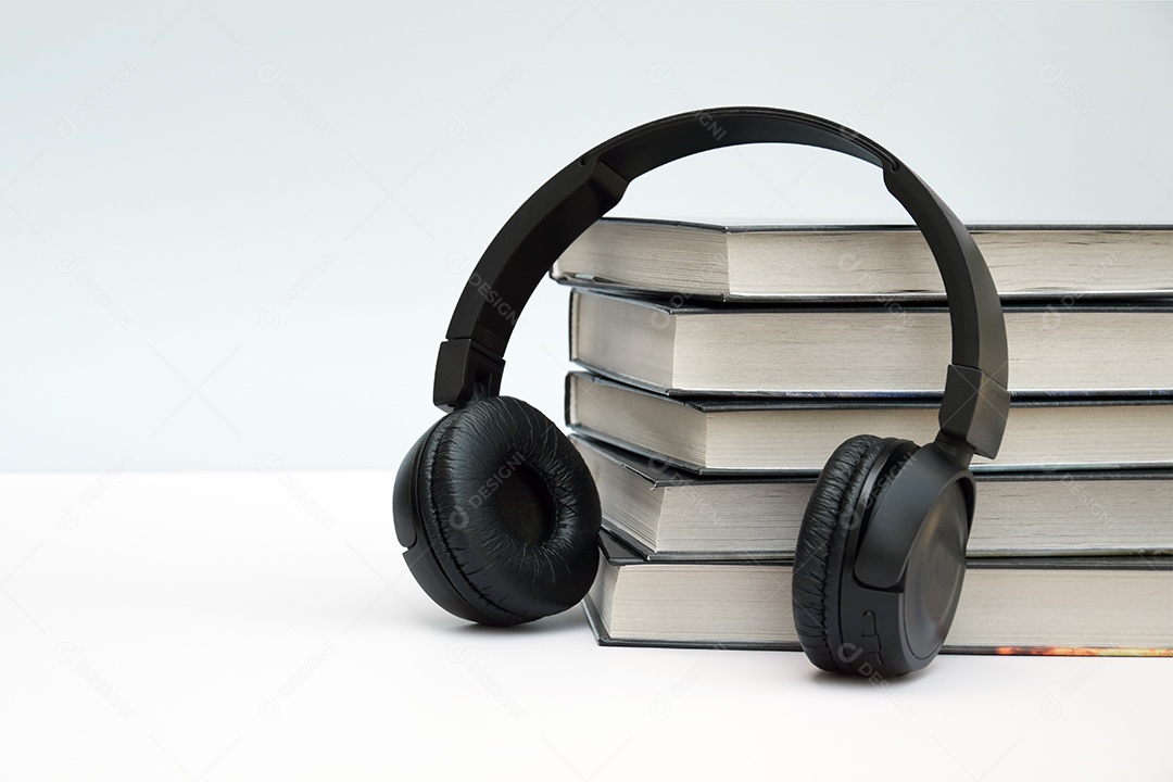 Muitos livros com fone encostado sobre fundo claro