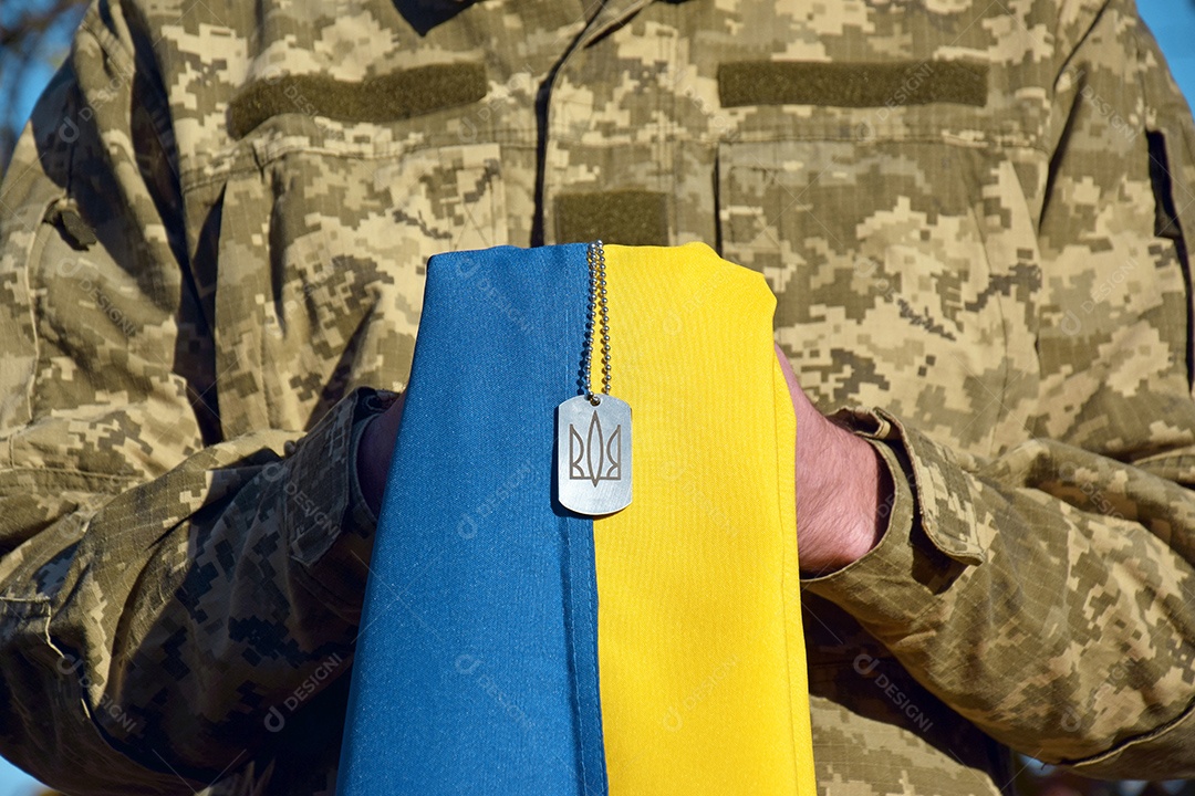 Um militar segurando bandeira e medalha com brasão Ucraniano