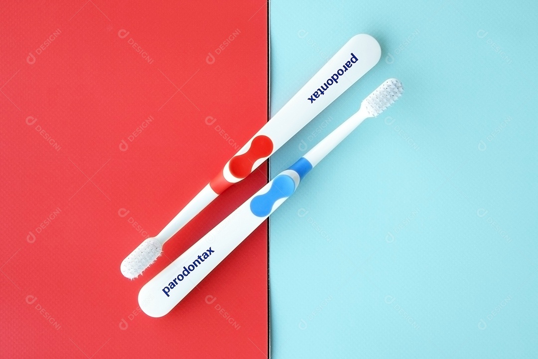 Escovas de dente sobre fundo de duas cores azul e vermelha