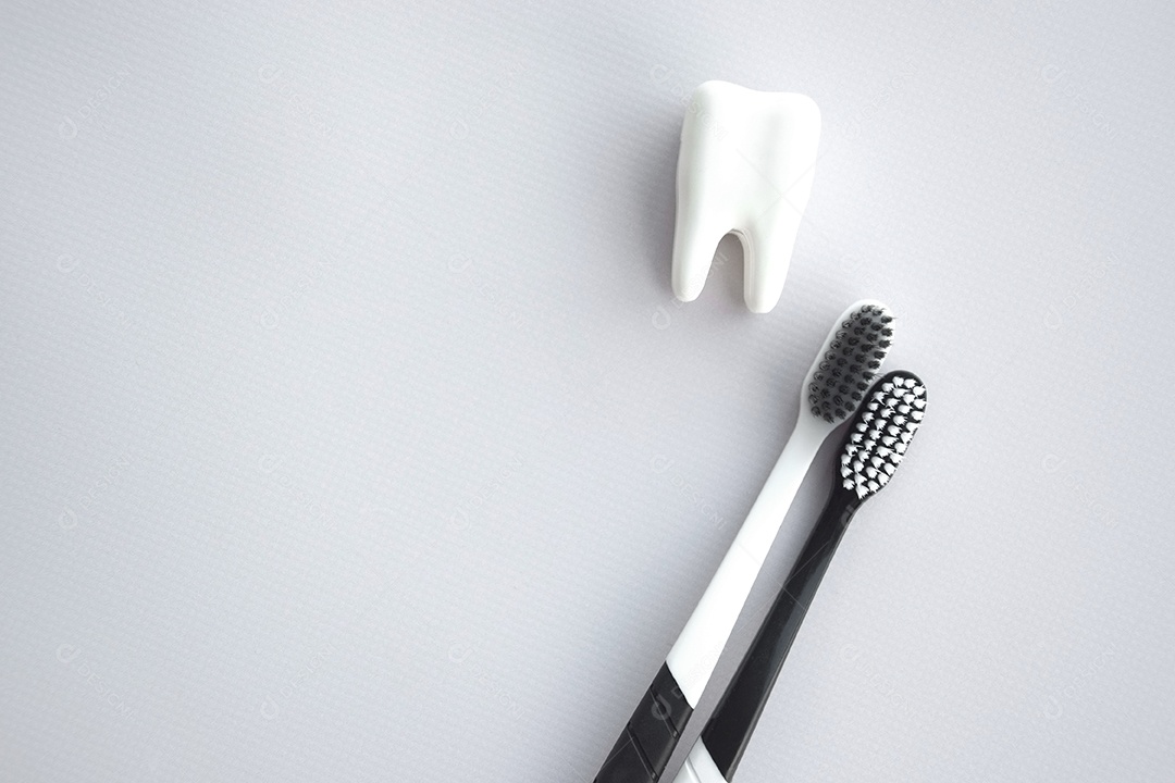 Duas escovas de dente com figura de dente ao lado conceito de saúde bucal