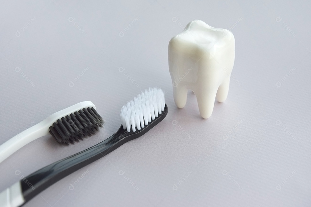 Duas escovas de dente com figura de dente ao lado conceito de saúde bucal