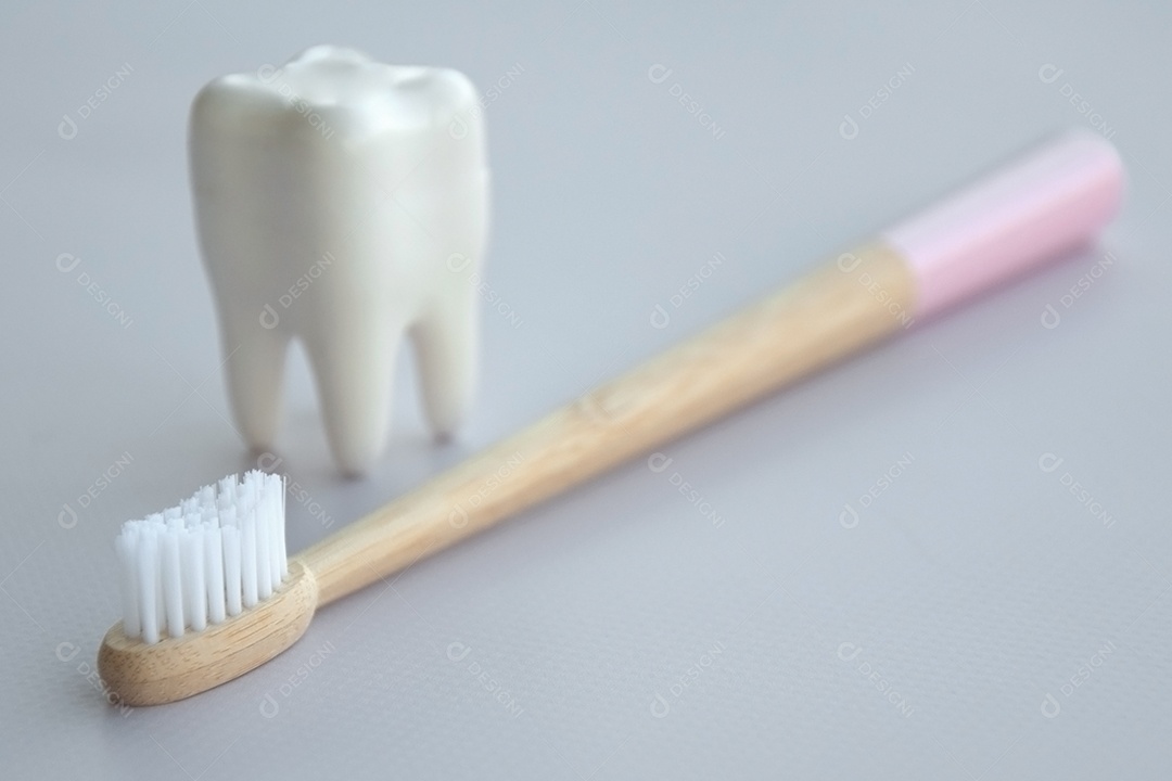 Escova de bambu do cabo rosa e figura de dente sobre fundo claro