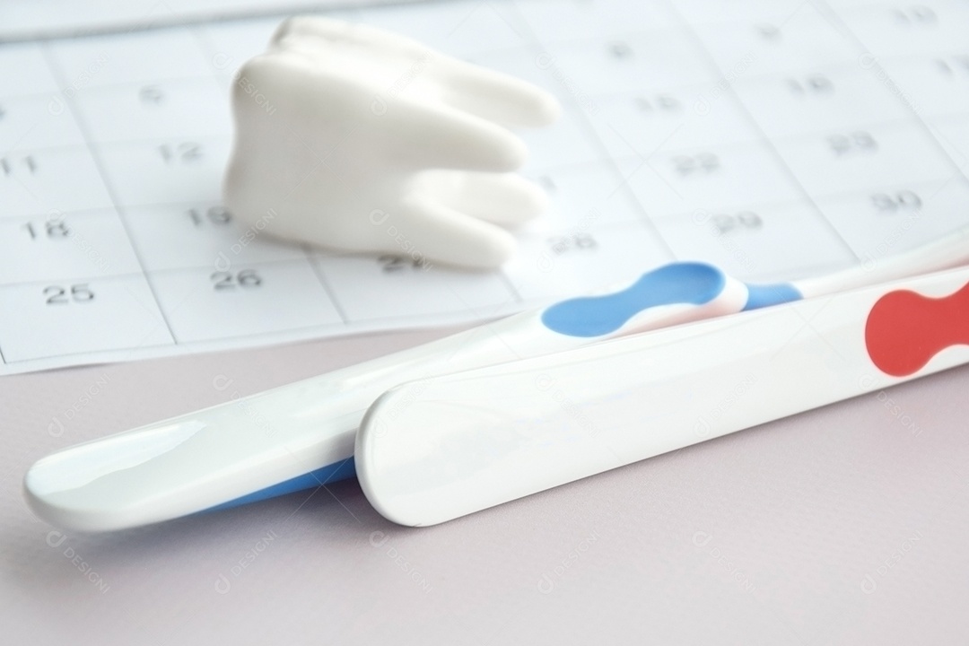 Escovas de dentes com uma pequena figura de dente sobre um fundo claro