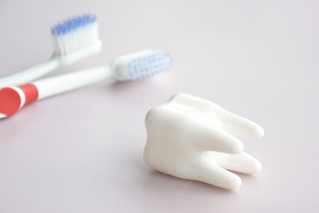 Escovas de dentes com uma pequena figura de dente sobre um fundo claro