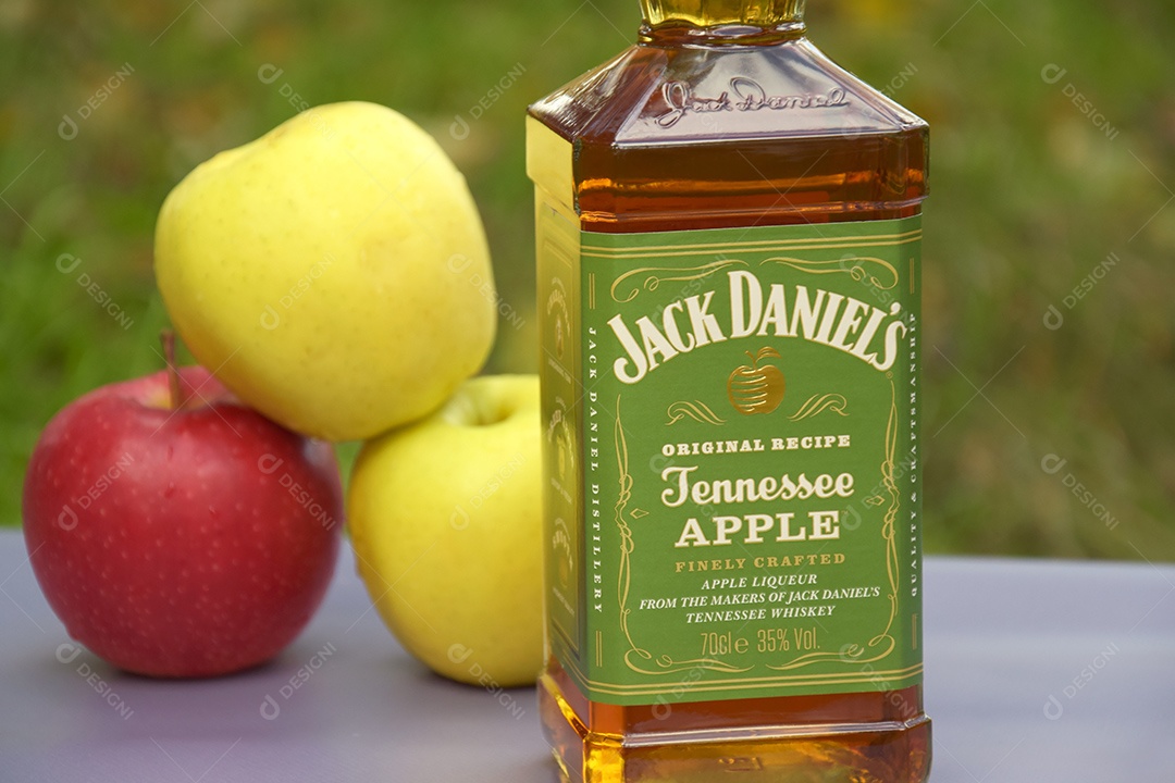 Maças e garrafa de whisky Jack Daniel´s sobre fundo natural