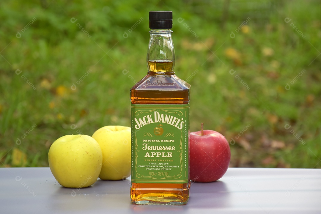 Garrafa de whisky Jack Daniel´s com maçãs ao lado e fundo natural