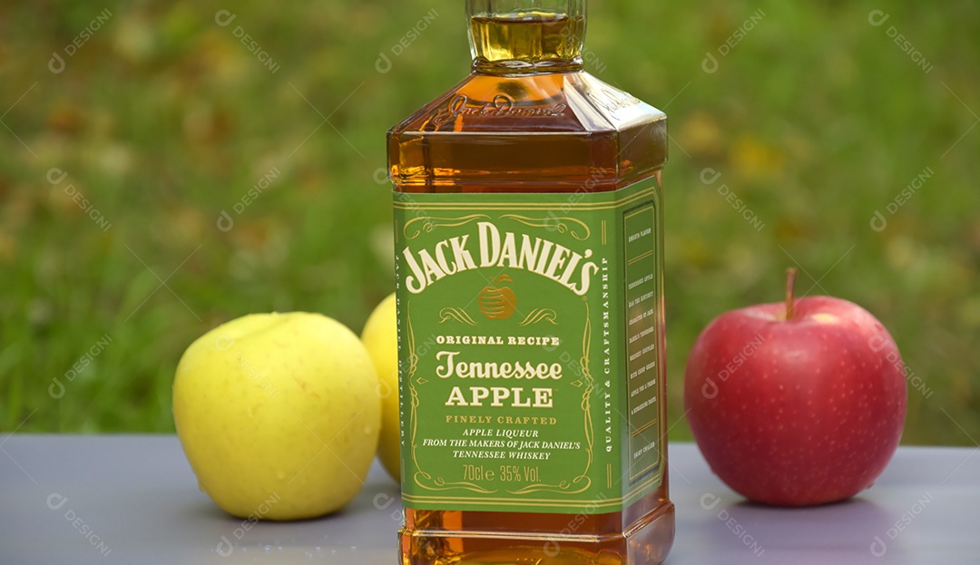 Garrafa de whisky Jack Daniel´s com maçãs ao lado e fundo natural