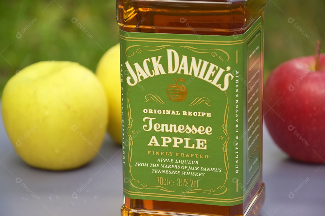 Garrafa de whisky Jack Daniel´s com maçãs ao lado e fundo natural