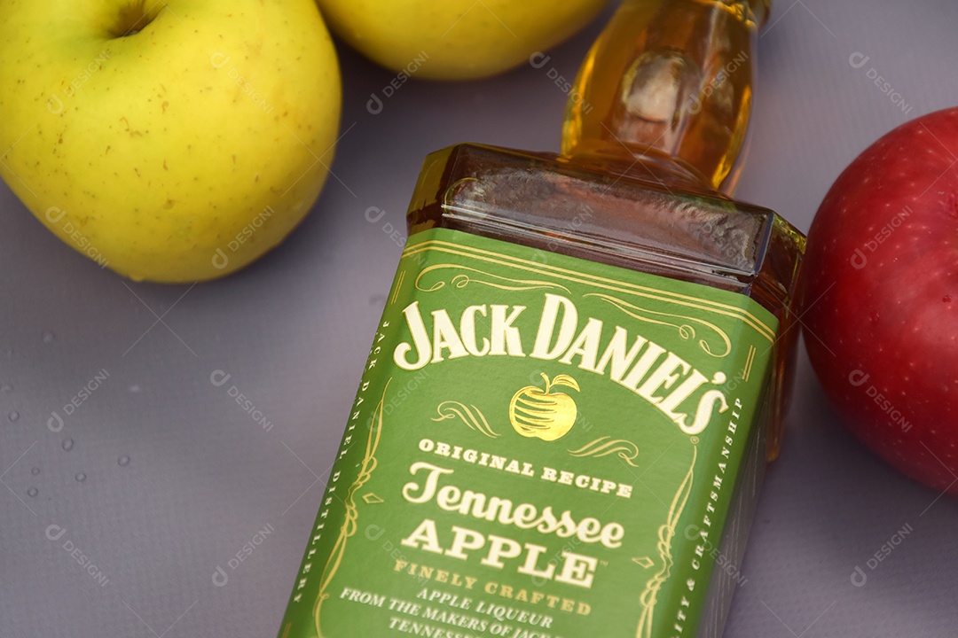 Garrafa de Jack Daniels com sabores Maçã com algumas maçãs ao lado sobre fundo claro