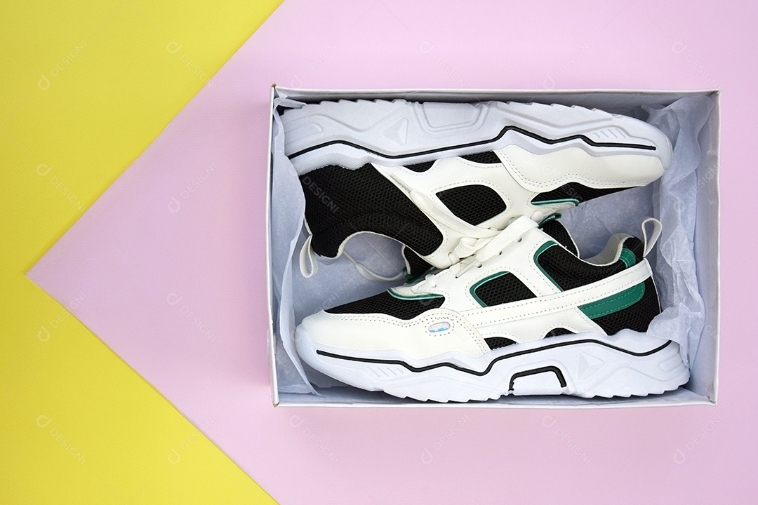 Caixa com tênis femininos brilhantes em fundo amarelo e rosa claro