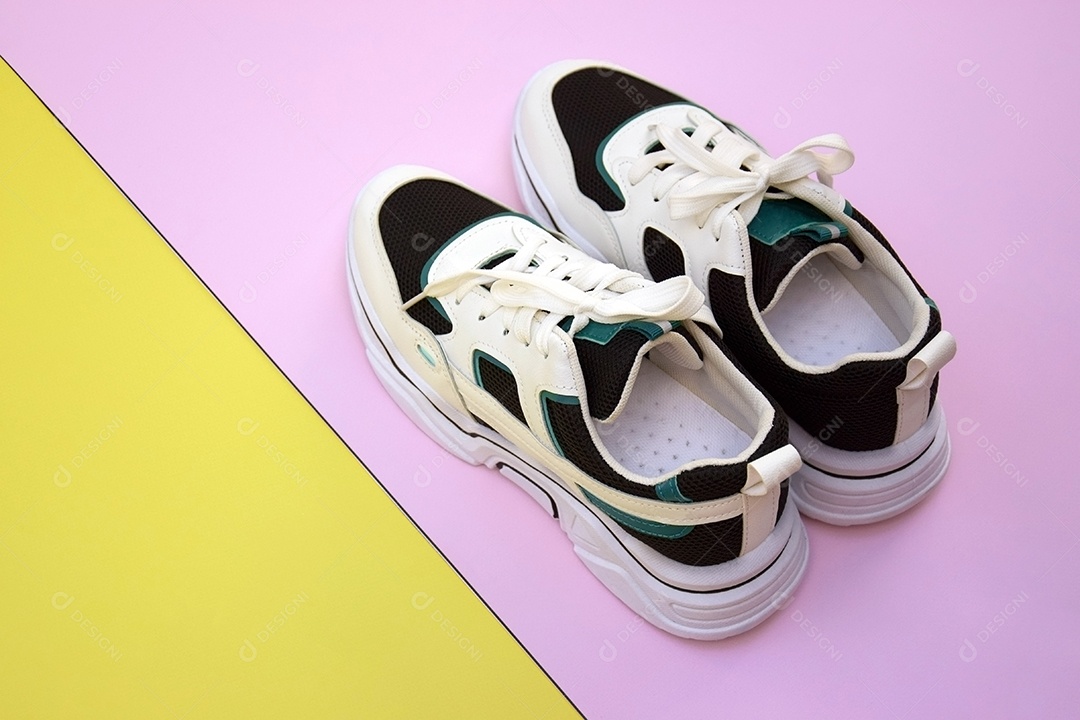 Um par de tênis sobre fundo rosa e amarelo