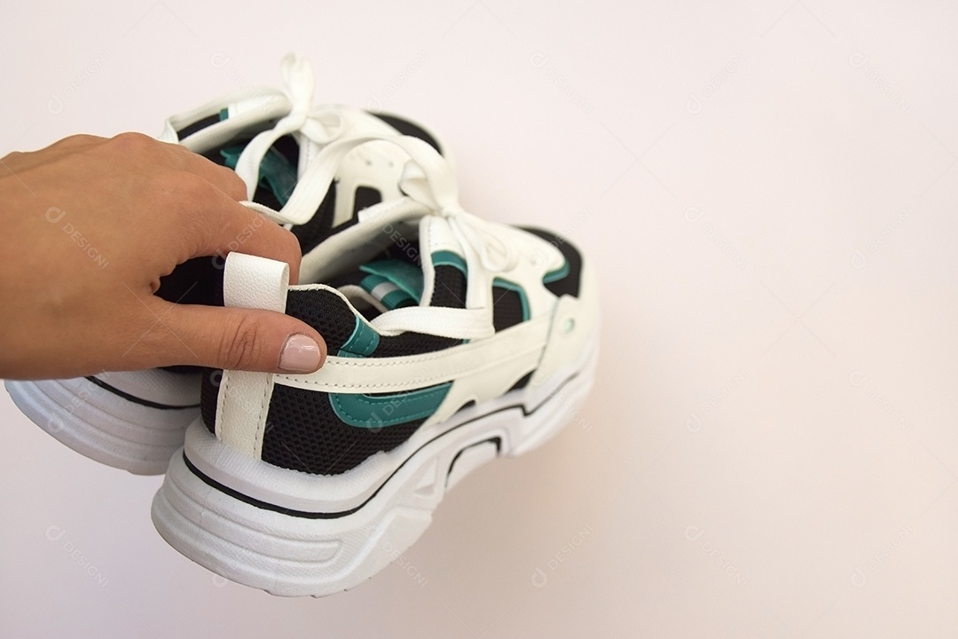 Mão segurando tênis mostrando detalhes na parte de trás