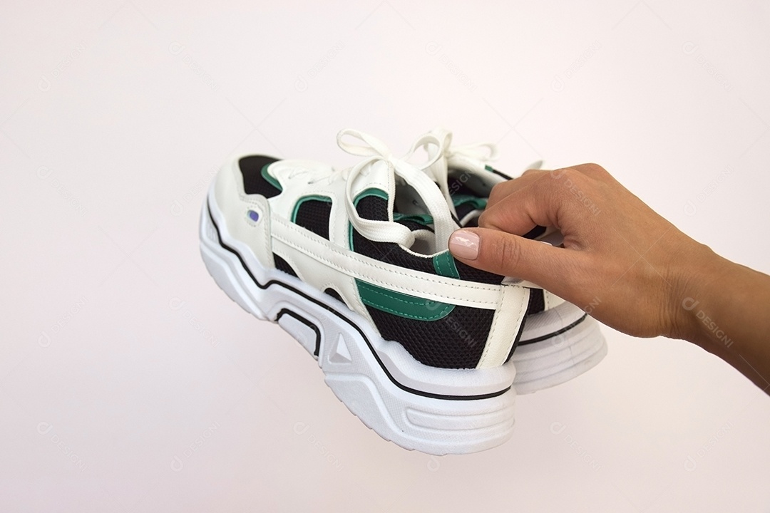 Mão segurando tênis mostrando detalhes na parte de trás