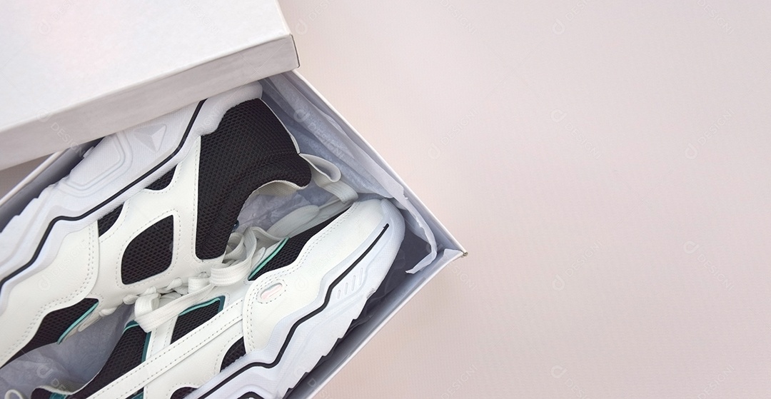 Caixa com tênis femininos brilhantes em fundo rosa claro