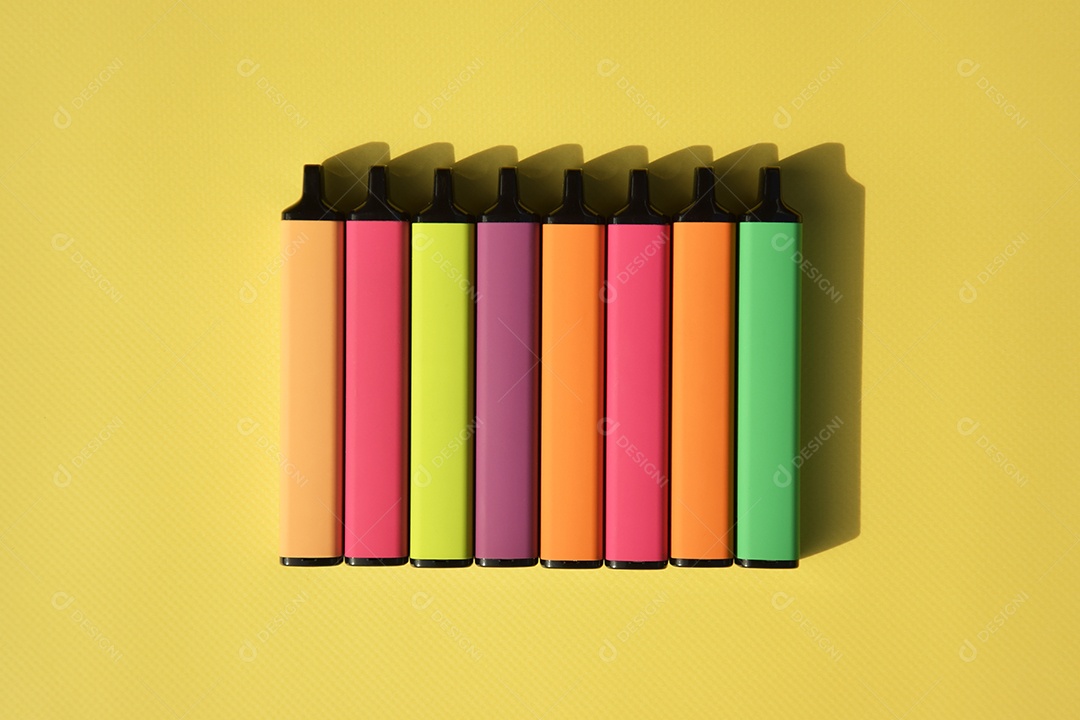 Muitos cigarros eletrônicos descartáveis ​​multicoloridos em um fundo amarelo