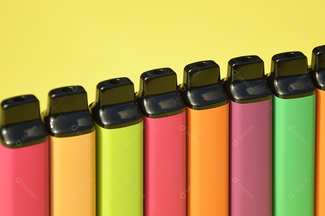 Cigarros eletrônico coloridos sobre fundo amarelo