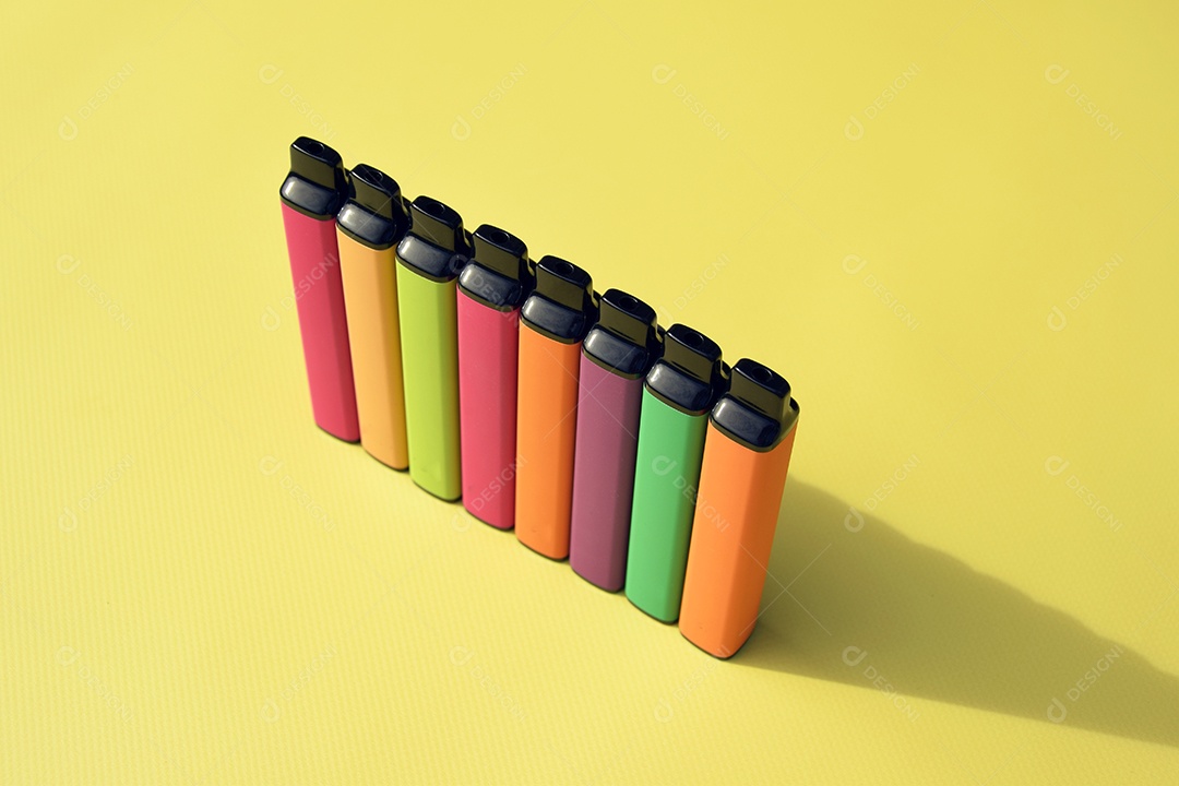 Cigarros eletrônico coloridos sobre fundo amarelo