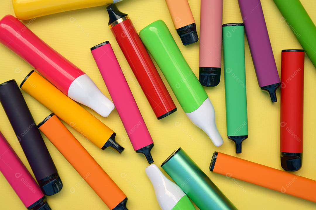 Vários cigarros eletrônicos descartáveis ​​multicoloridos em um fundo amarelo