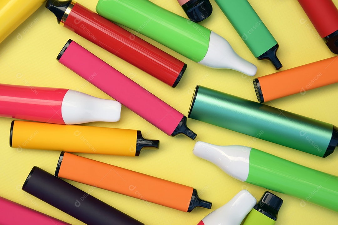 Muitos cigarros eletrônicos descartáveis ​​multicoloridos em um fundo amarelo
