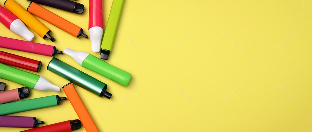 Vários cigarros eletrônicos descartáveis ​​multicoloridos em um fundo amarelo