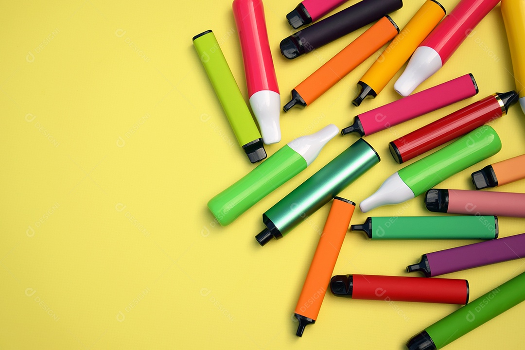 Muitos cigarros eletrônicos descartáveis ​​multicoloridos em um fundo amarelo