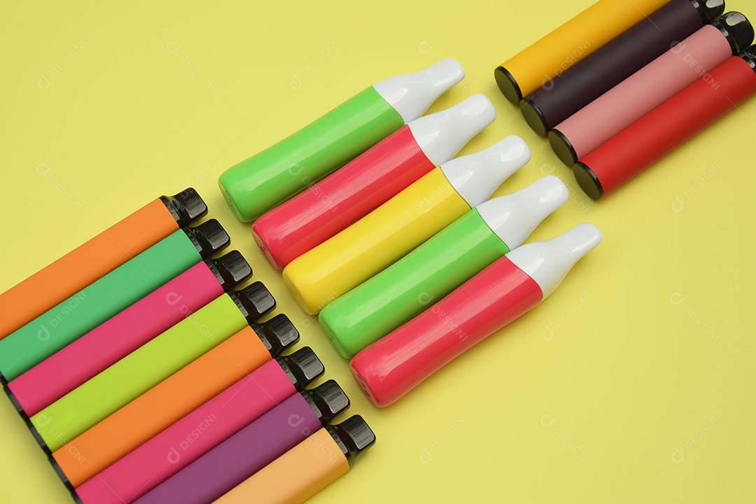 Conjunto de cigarros eletrônicos descartáveis ​​multicoloridos em um fundo amarelo brilhante