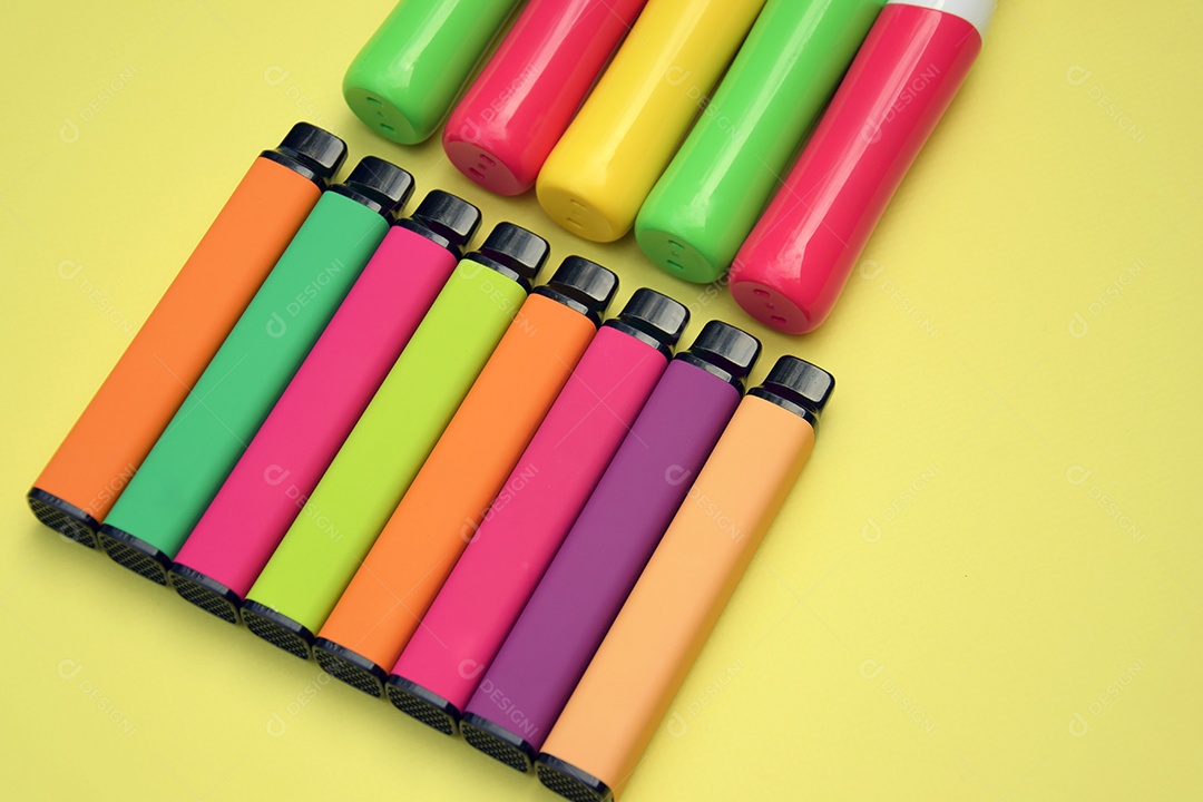Muitos cigarros eletrônicos descartáveis ​​multicoloridos em um fundo amarelo