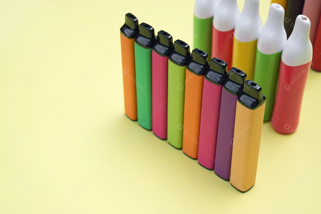 Cigarros eletrônico coloridos sobre fundo amarelo