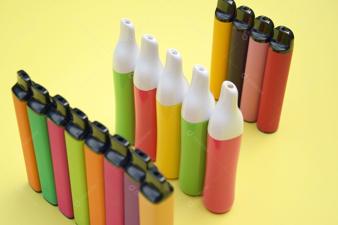 Cigarros eletrônico coloridos sobre fundo amarelo