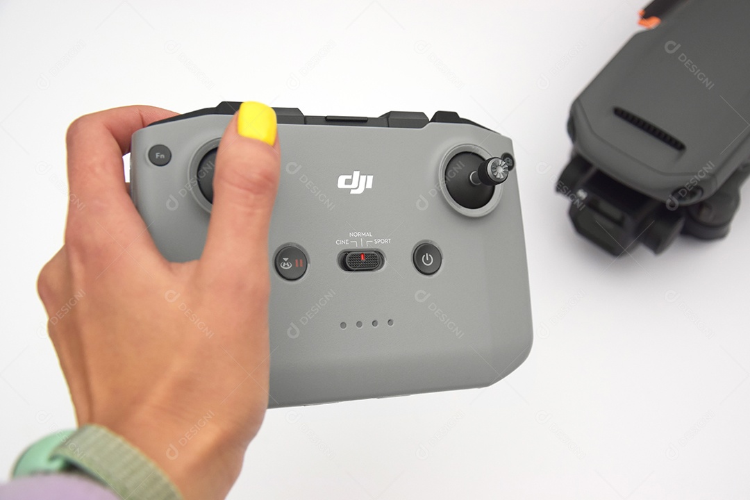 Mão segurando controle de drone mavic 3 contra mesa branca