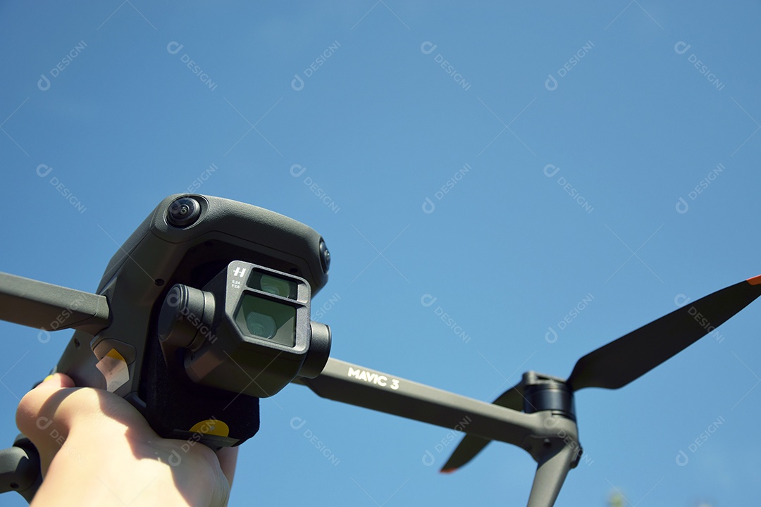 Mão segurando drone mavic 3 contra céu azul