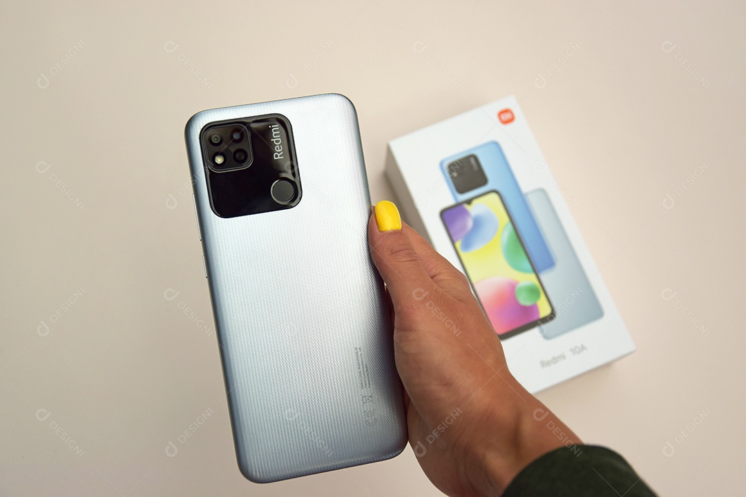 Mão feminina segurando Novo celular da Xiaomi Redmi 10A sobre fundo claro