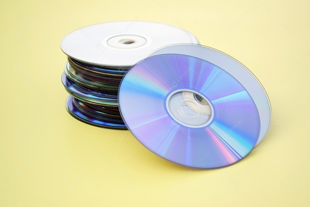 Pilha de CDs antigos sobre fundo amarelo