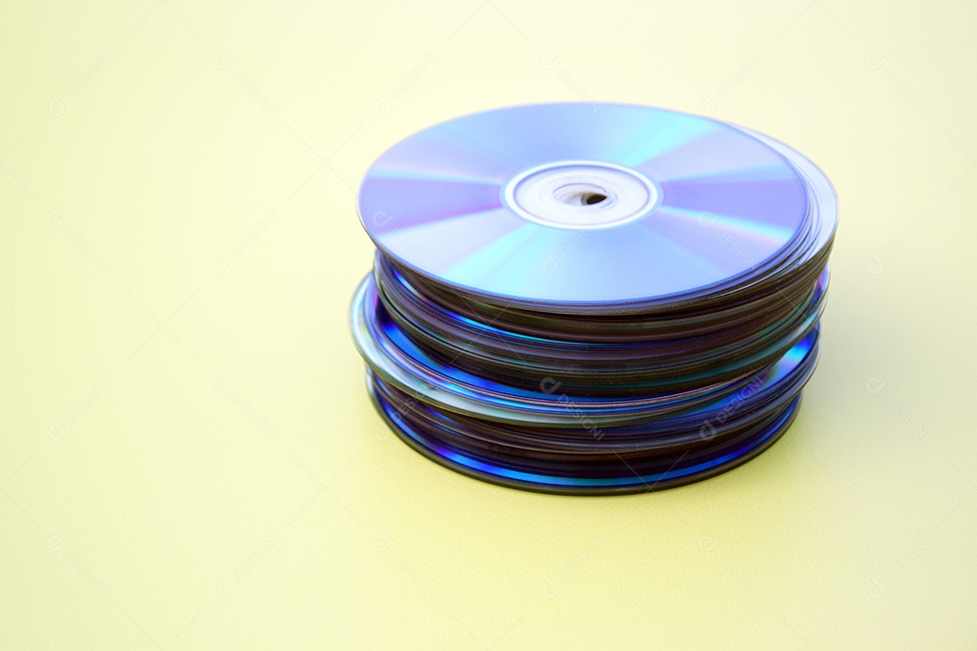Pilha de CDs antigos sobre fundo amarelo