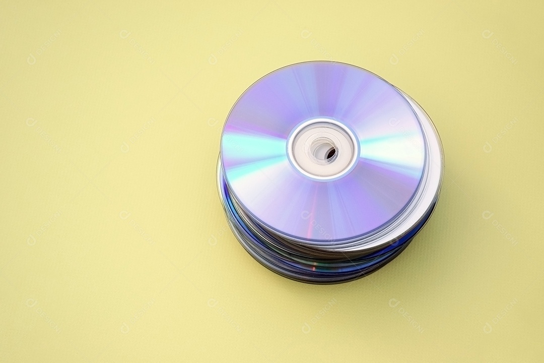 Pilha de CDs antigos sobre fundo amarelo