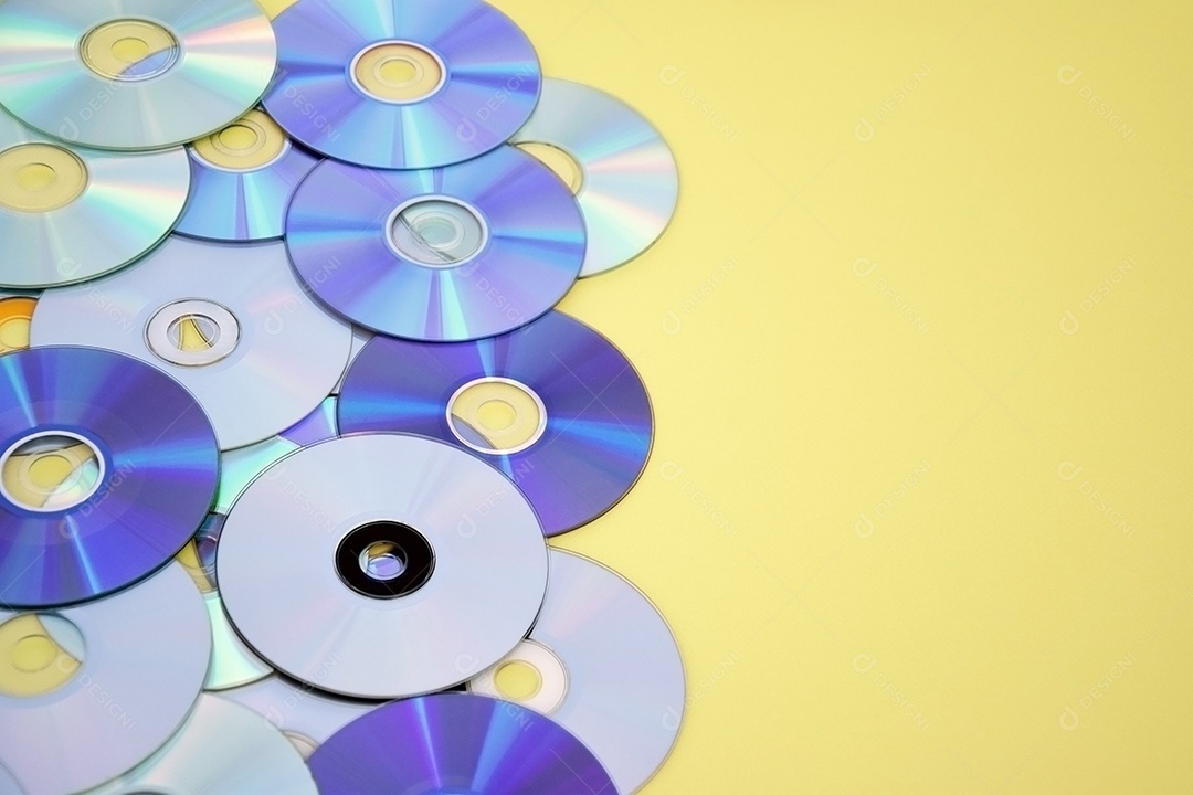 Vários CDs antigos estão dispostos sobre fundo amarelo