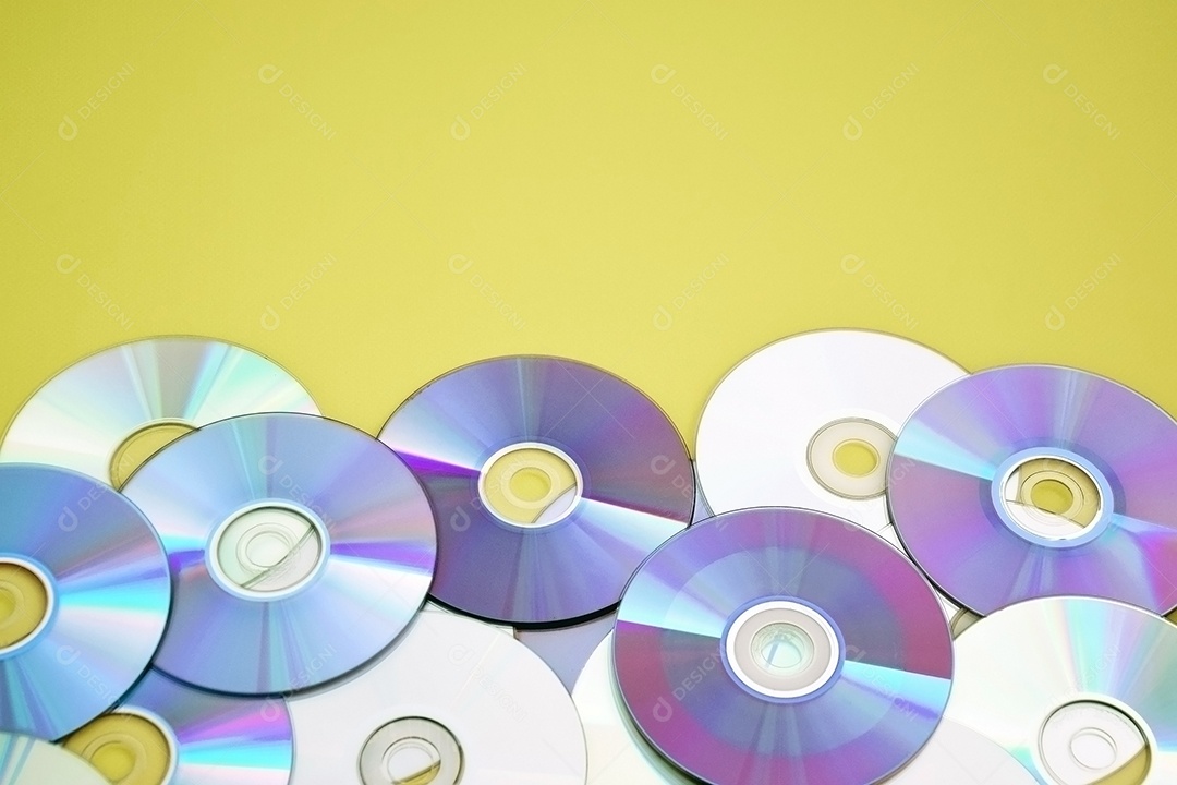 Vários CDs antigos estão dispostos sobre fundo amarelo