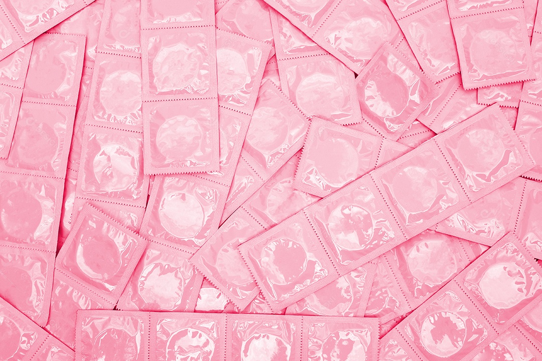 Muitos preservativos sobre fundo rosa claro