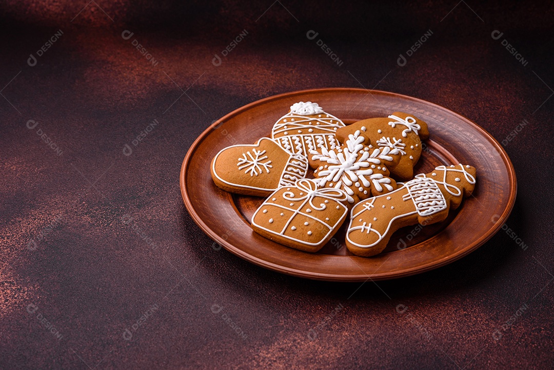 Lindos biscoitos de gengibre de Natal de cores diferentes em uma placa de cerâmica sobre uma mesa de concreto escuro