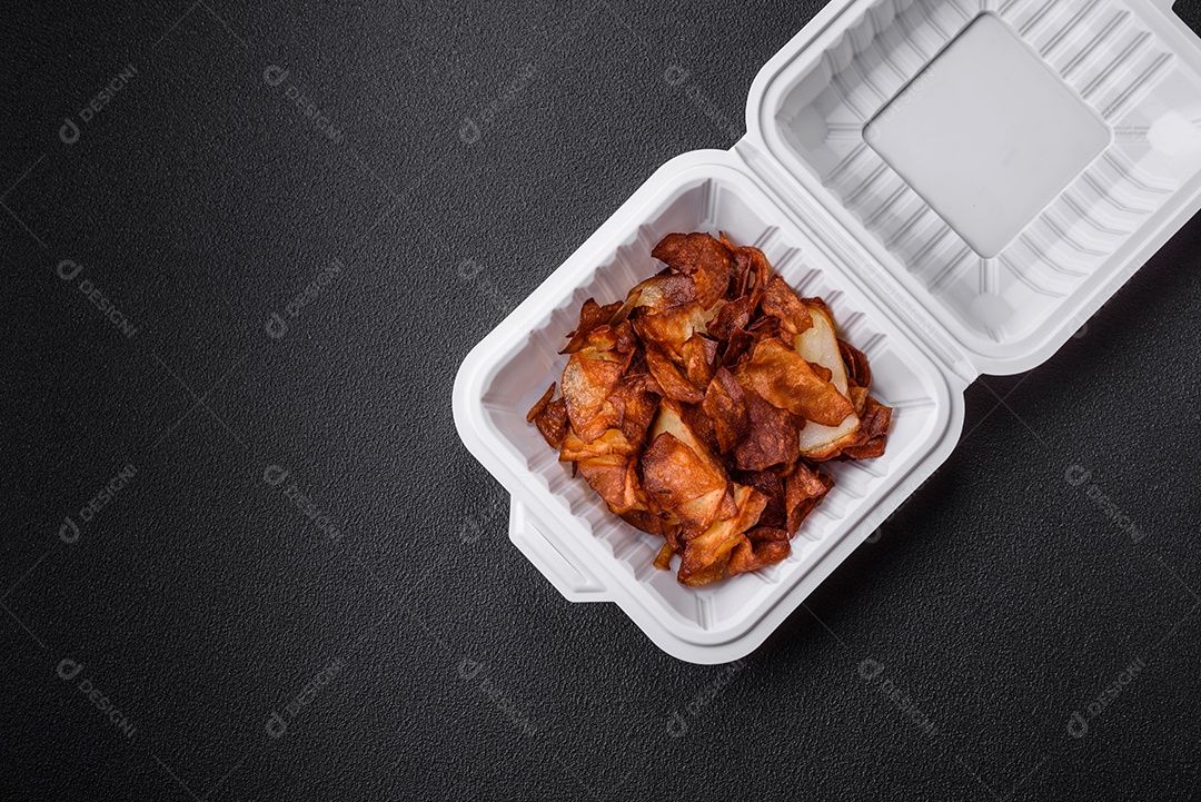 Deliciosas batatas fritas crocantes com sal e especiarias em um fundo escuro de concreto