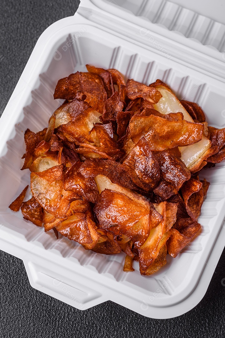 Deliciosas batatas fritas crocantes com sal e especiarias em um fundo escuro de concreto