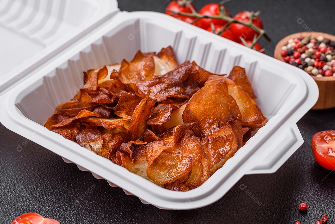 Deliciosas batatas fritas crocantes com sal e especiarias em um fundo escuro de concreto