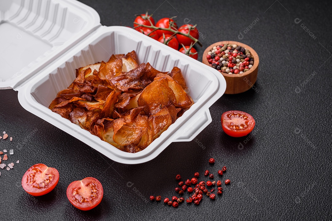 Deliciosas batatas fritas crocantes com sal e especiarias em um fundo escuro de concreto