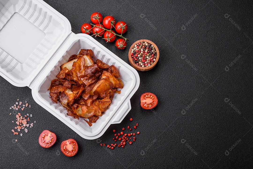 Deliciosas batatas fritas crocantes com sal e especiarias em um fundo escuro de concreto